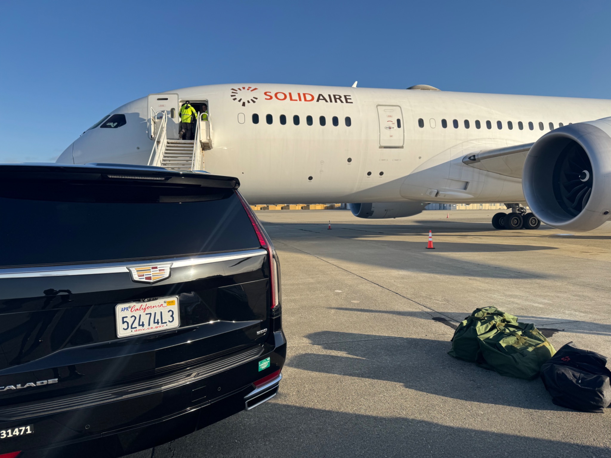 Black Cadillac Escalade positioned beside a passenger aircraft
