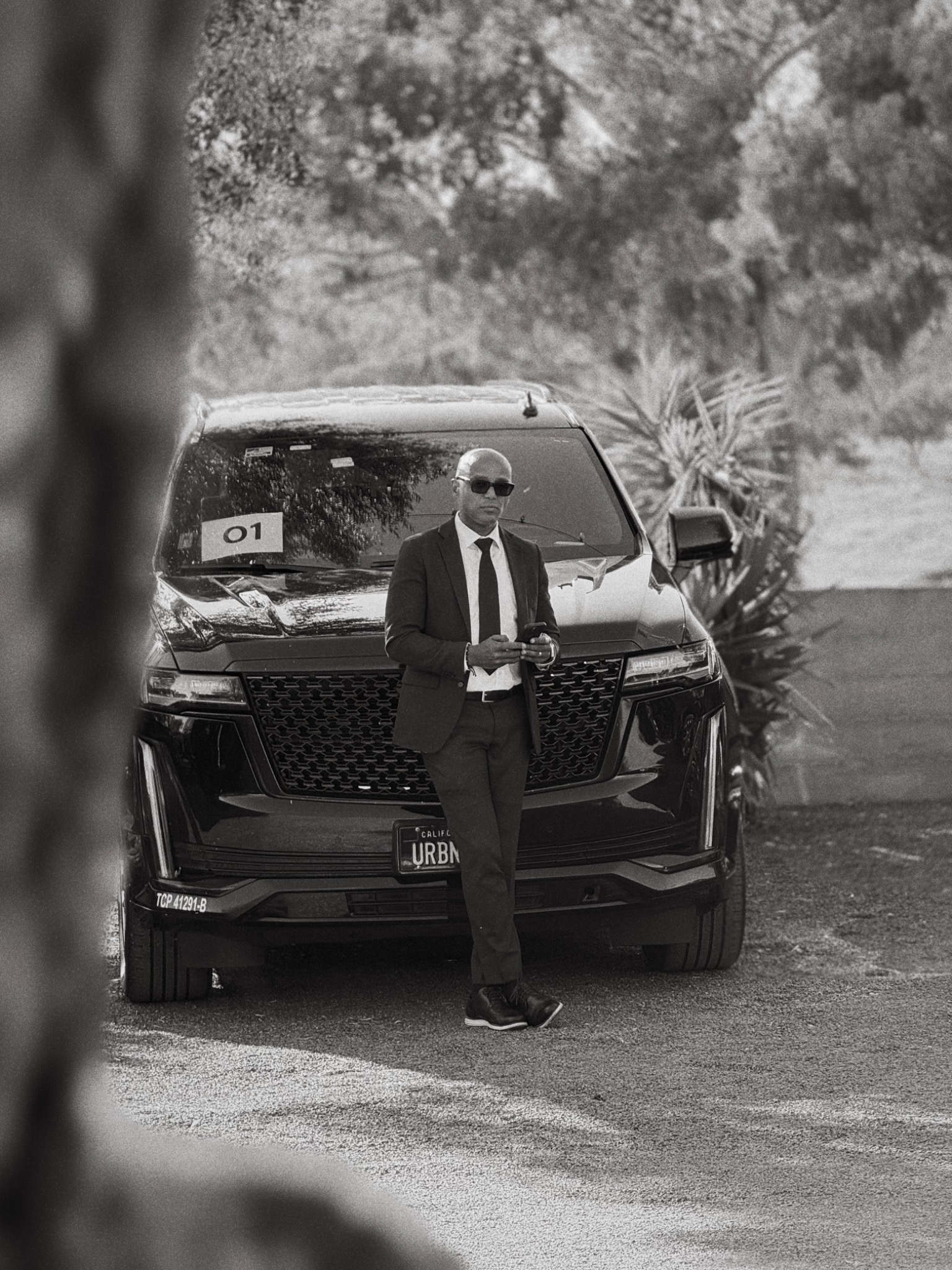 Professional chauffeur standing in front of a Cadillac Escalade