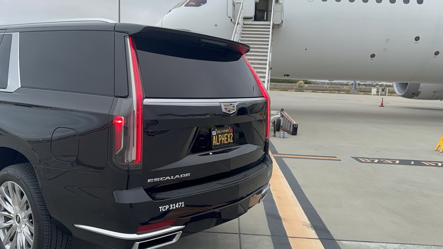 Black Cadillac Escalade parked beside a private jet